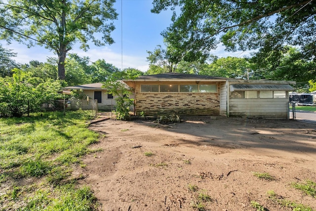 back of house featuring fence, brick siding, and a gate