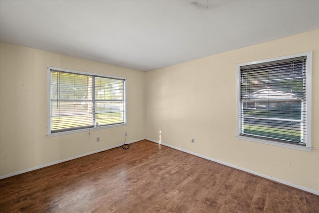 spare room featuring baseboards and wood finished floors