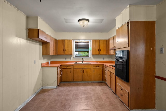 kitchen with black appliances, a sink, brown cabinets, and light countertops