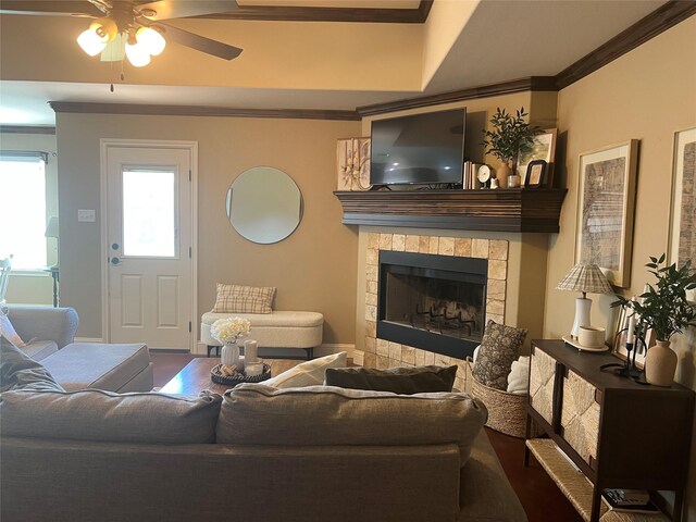 living room with crown molding, wood finished floors, a ceiling fan, and a tiled fireplace