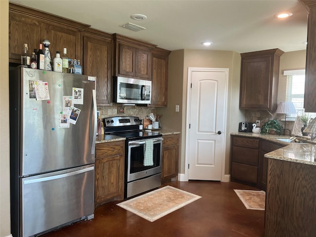 kitchen with appliances with stainless steel finishes, tasteful backsplash, light stone countertops, a sink, and recessed lighting
