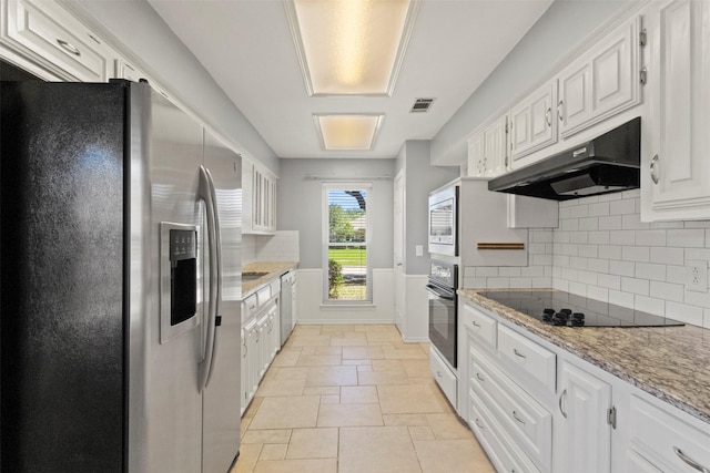 kitchen featuring black appliances, under cabinet range hood, stone tile flooring, and white cabinets