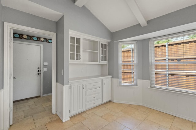 kitchen featuring white cabinetry, open shelves, a wainscoted wall, light countertops, and light stone finish flooring
