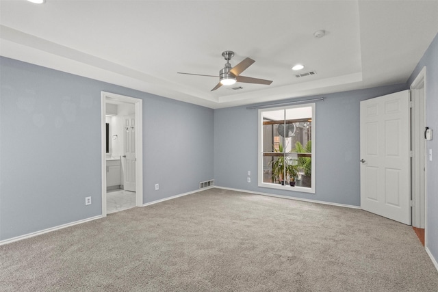 unfurnished bedroom featuring a raised ceiling, carpet floors, baseboards, recessed lighting, and connected bathroom