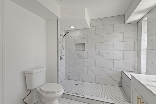 bathroom with marble finish flooring, toilet, tiled shower, and vanity