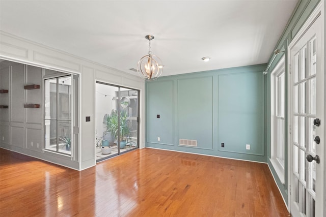 empty room featuring a decorative wall, wood finished floors, and a chandelier