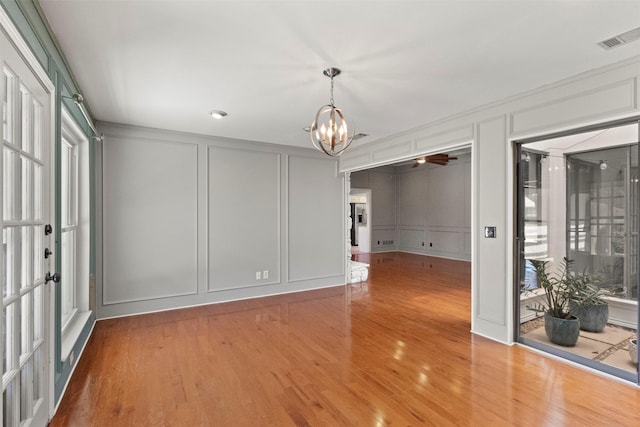 unfurnished room featuring a decorative wall, a chandelier, and wood finished floors