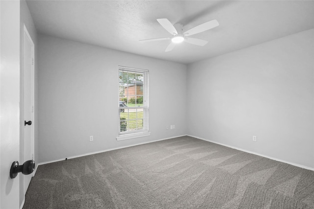 carpeted spare room with a ceiling fan and baseboards