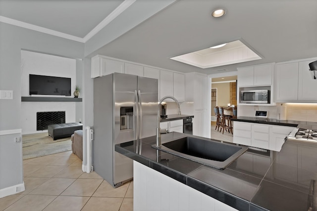 1503 Hindsdale Dr, Richardson, TX 75081 - kitchen featuring stainless steel appliances, white cabinets, light tile patterned floors, ornamental molding, and a fireplace