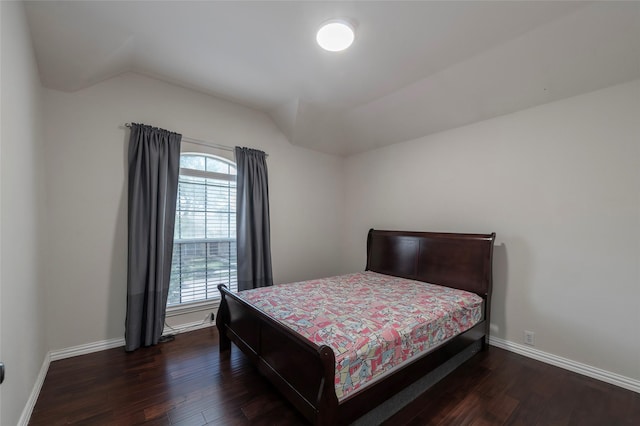 bedroom featuring dark wood-style floors, lofted ceiling, and baseboards