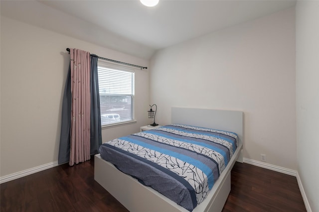 bedroom featuring wood finished floors, lofted ceiling, and baseboards