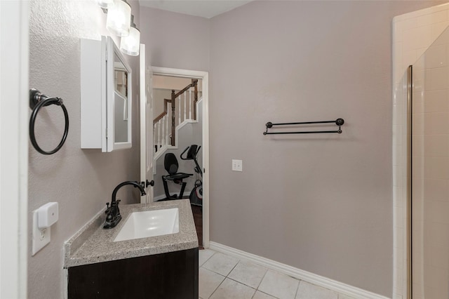 bathroom with tile patterned flooring, baseboards, vanity, and tiled shower