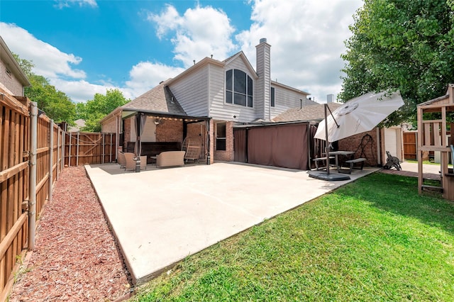 rear view of house featuring a patio area, a chimney, a shingled roof, and brick siding