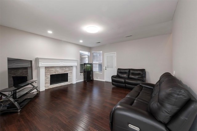 living room featuring a stone fireplace, wood finished floors, recessed lighting, and baseboards