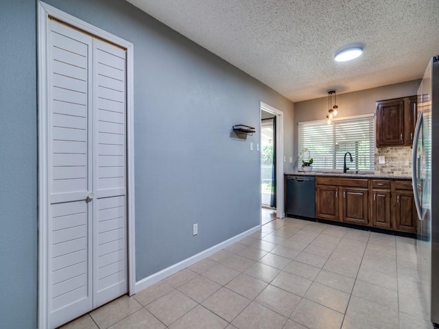 kitchen featuring black dishwasher, freestanding refrigerator, a textured ceiling, tasteful backsplash, and a sink