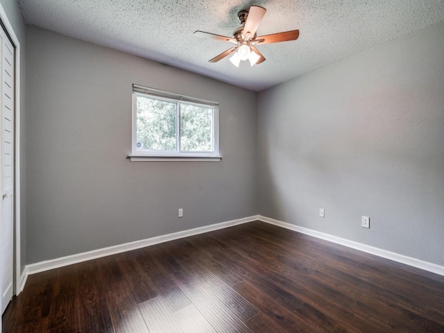 empty room with a ceiling fan, dark wood-type flooring, baseboards, and a textured ceiling