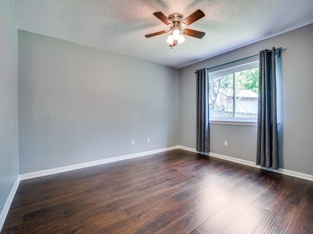 spare room featuring ceiling fan, dark wood finished floors, a textured ceiling, and baseboards