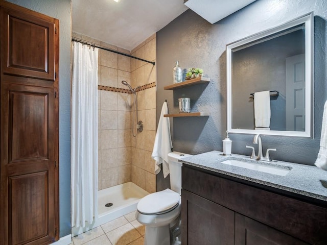 bathroom with a textured wall, tile patterned floors, tiled shower, toilet, and vanity