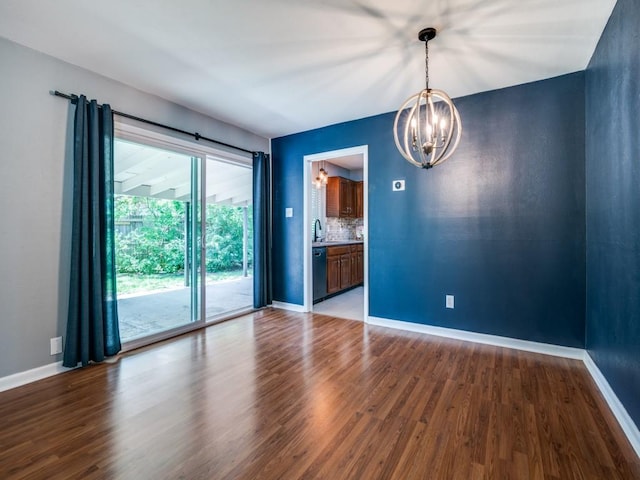 empty room featuring a chandelier, wood finished floors, and baseboards