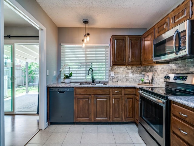 kitchen with appliances with stainless steel finishes, a sink, tasteful backsplash, healthy amount of natural light, and a textured ceiling