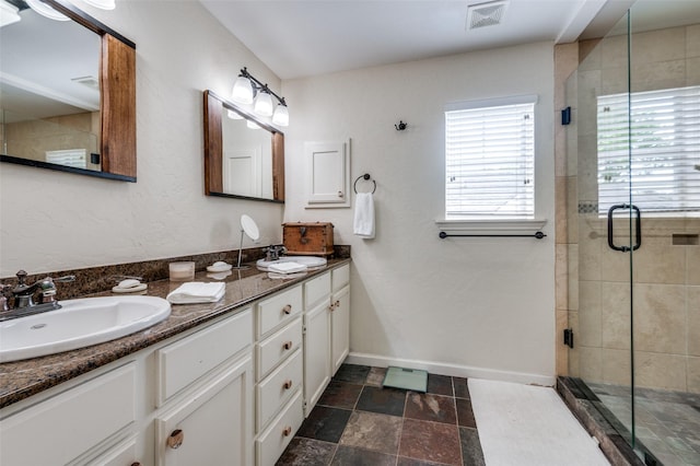 full bath featuring a stall shower, double vanity, and baseboards