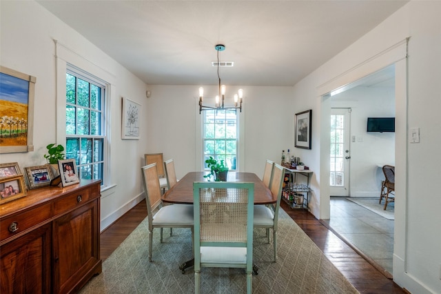 dining space featuring dark wood-type flooring, a chandelier, and baseboards