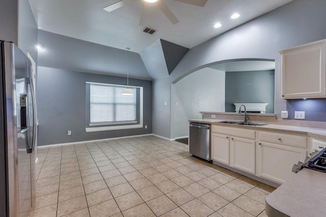 kitchen featuring appliances with stainless steel finishes, a sink, arched walkways, a ceiling fan, and light countertops