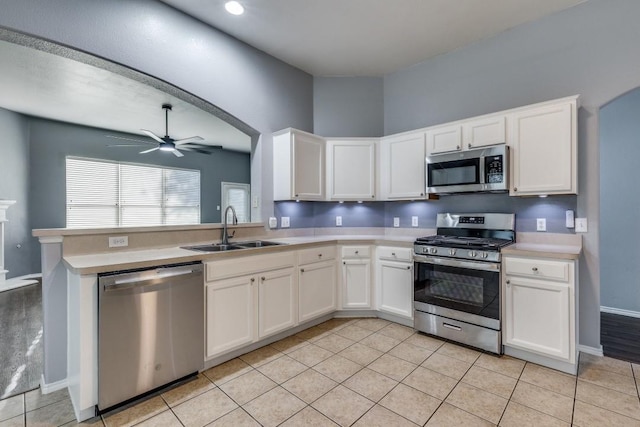 kitchen with stainless steel appliances, a sink, ceiling fan, light countertops, and white cabinetry
