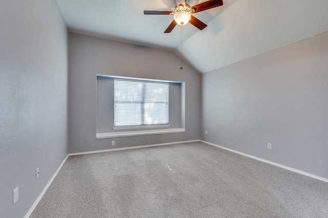 carpeted spare room featuring ceiling fan, vaulted ceiling, and baseboards