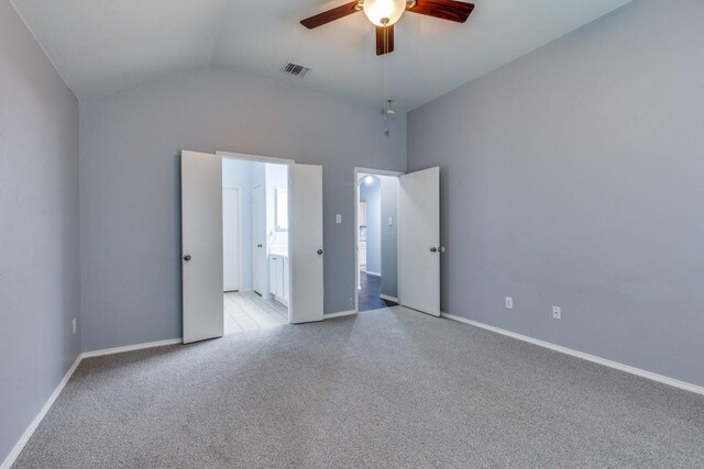 unfurnished bedroom featuring light colored carpet, vaulted ceiling, baseboards, ensuite bathroom, and a ceiling fan