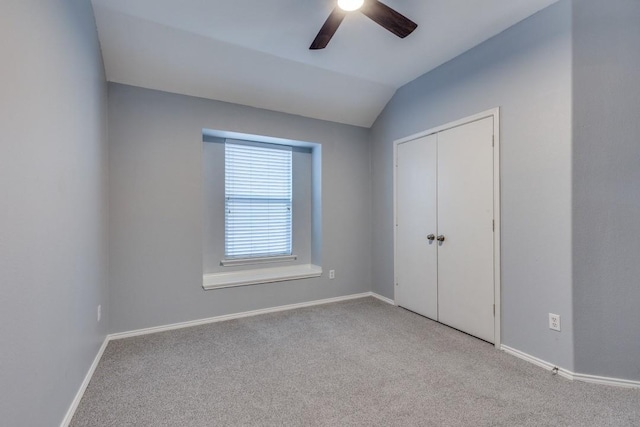 unfurnished bedroom featuring carpet flooring, baseboards, a closet, and vaulted ceiling