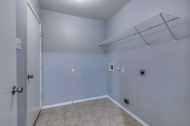 laundry room featuring electric dryer hookup, hookup for a washing machine, light tile patterned flooring, and baseboards