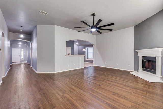 unfurnished living room with a ceiling fan, arched walkways, and wood finished floors