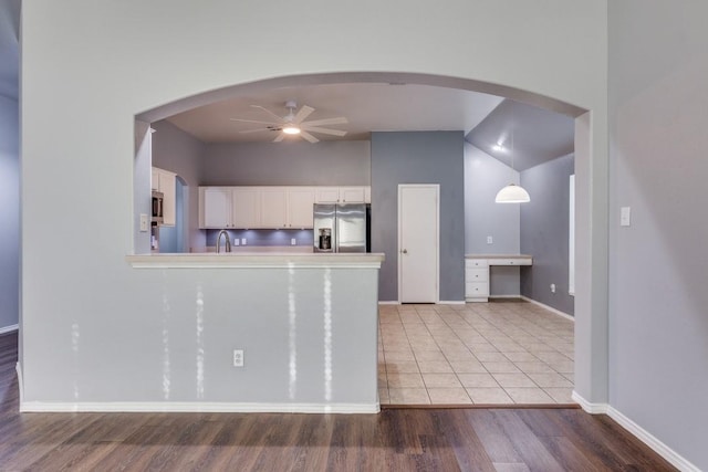 kitchen featuring stainless steel appliances, a ceiling fan, light wood finished floors, white cabinetry, and light countertops