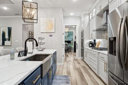 2230 Rana Park, Flint, TX 75762 - kitchen featuring stainless steel appliances, blue cabinetry, wall chimney range hood, a chandelier, and light wood-style flooring