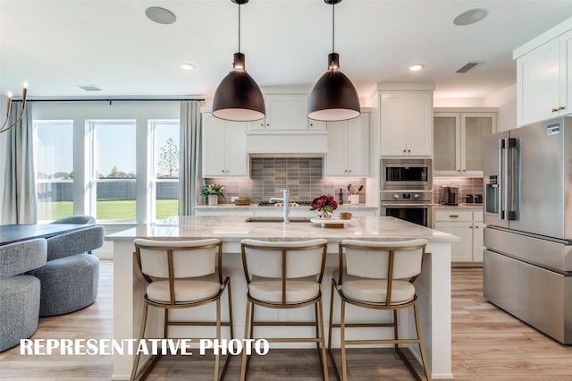 2316 Lakelet Dr, Mckinney, TX 75071 - kitchen with stainless steel appliances, tasteful backsplash, light stone countertops, white cabinetry, and a kitchen bar