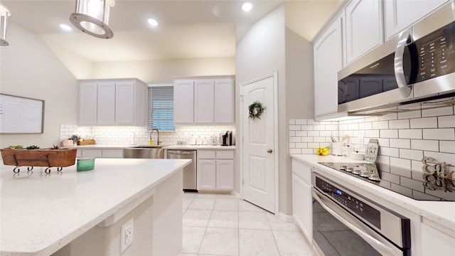 kitchen with stainless steel appliances, a sink, backsplash, white cabinetry, and light tile patterned flooring