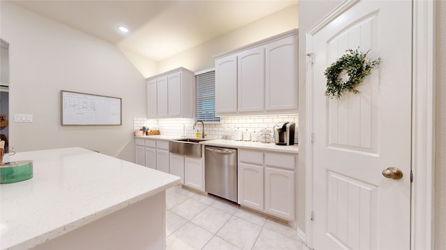 kitchen with stainless steel dishwasher, a sink, decorative backsplash, light tile patterned flooring, and white cabinets