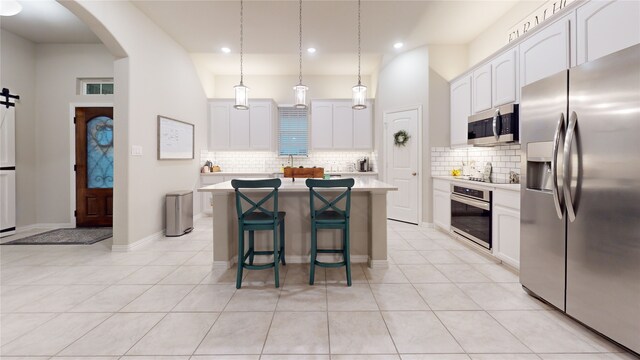 kitchen featuring stainless steel appliances, light countertops, arched walkways, backsplash, and white cabinetry