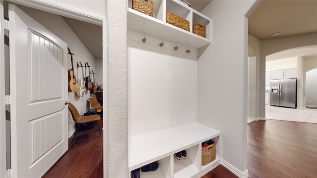 mudroom with arched walkways, light wood finished floors, and baseboards