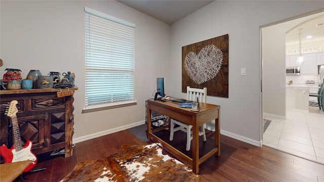 office featuring wood finished floors, baseboards, and arched walkways