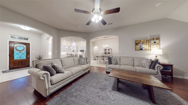 living area featuring arched walkways, a ceiling fan, wood finished floors, and baseboards