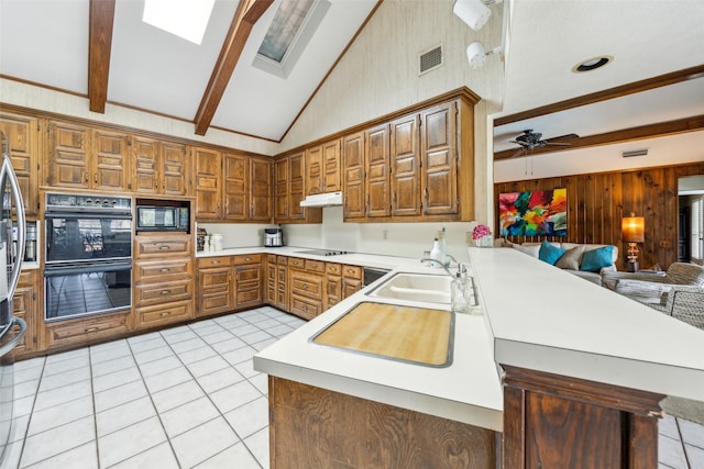 kitchen with a sink, black appliances, light tile patterned floors, open floor plan, and light countertops