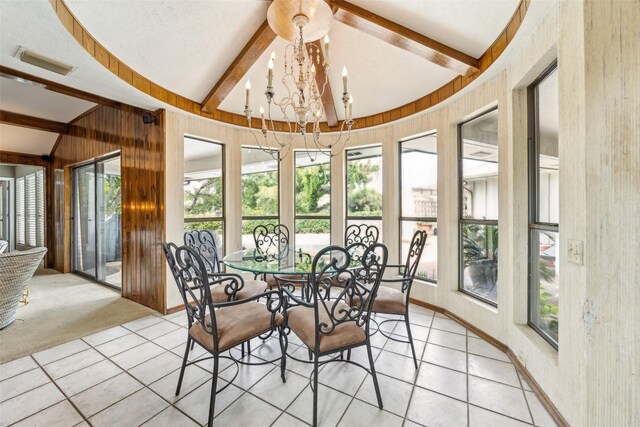sunroom / solarium featuring tile patterned floors, wooden walls, healthy amount of natural light, and a chandelier