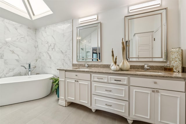full bath featuring double vanity, a freestanding tub, a skylight, tile walls, and tile patterned floors