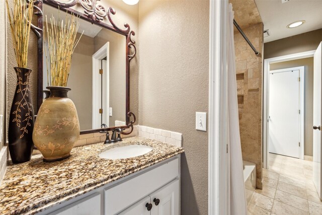 full bathroom with vanity, shower / tub combo, and a textured wall
