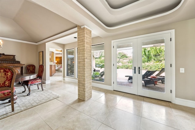 entryway with ornate columns, plenty of natural light, a tray ceiling, french doors, and vaulted ceiling