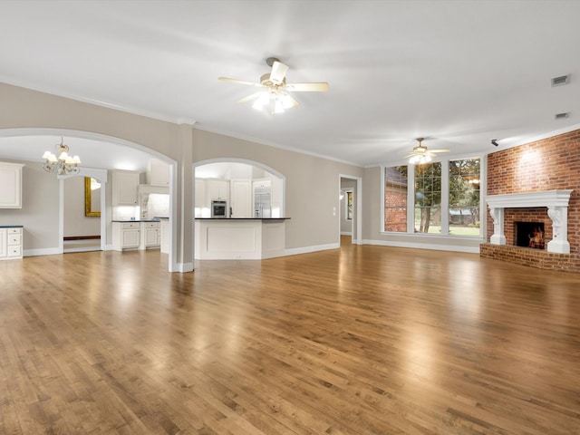 901 Saint James Dr, Fairview, TX 75069 - unfurnished living room featuring ceiling fan, a brick fireplace, a chandelier, wood finished floors, and crown molding