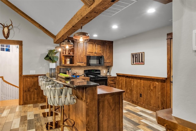 417 Windwood Ct, Mckinney, TX 75071 - kitchen featuring black appliances, light wood finished floors, wainscoting, a breakfast bar area, and brown cabinets