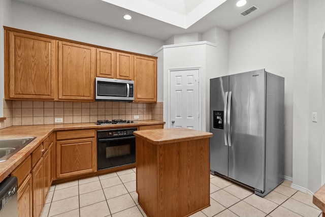 1060 Knightsbridge Dr, Frisco, TX 75036 - kitchen with appliances with stainless steel finishes, tasteful backsplash, a kitchen island, light tile patterned floors, and recessed lighting